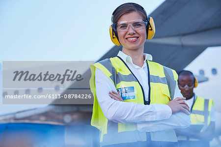 Portrait smiling female air traffic controller standing near airplane Portrait smiling female air traffic controller standing near airplane