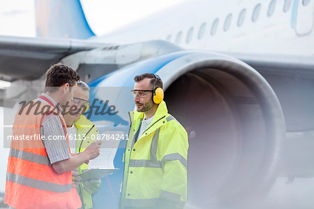 Air traffic control ground crew with clipboard next to airplane on tarmac