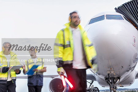 Air traffic controllers walking in front of airplane on airport tarmac