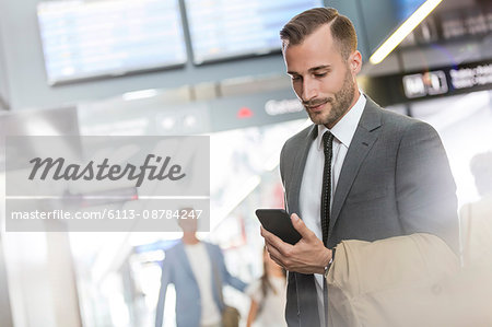 Businessman texting with cell phone in airport concourse