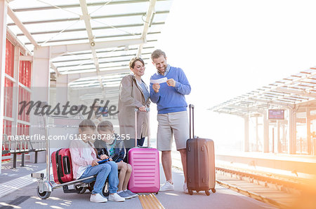 Family with suitcases waiting at train station platform