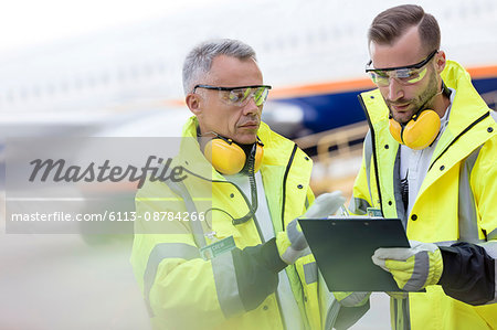 Air traffic controllers with clipboard talking on airport tarmac