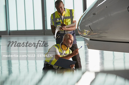 Airport ground crew workers examining airplane in hangar