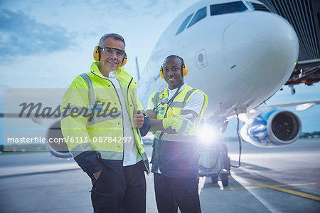 Portrait confident air traffic control ground crew workers near airplane on airport tarmac