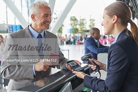 Customer service representative scanning smart phone QR code boarding pass at airport check-in counter