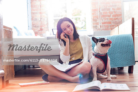 Woman talking on cell phone next to French Bulldog on floor