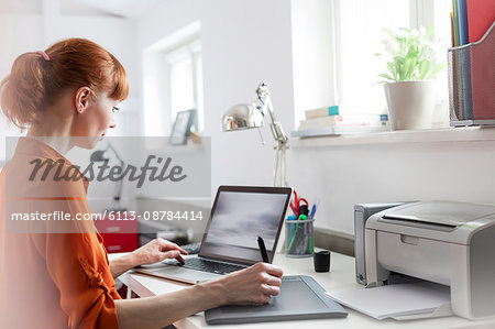 Designer using graphics tablet at laptop in office