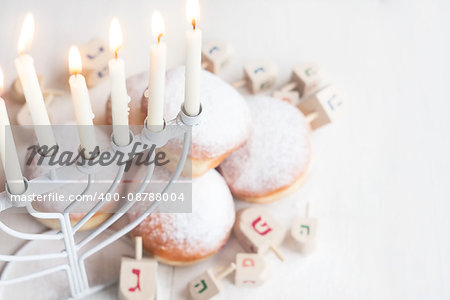 Jewish traditional holiday Hannukah with menorah, doughnuts and dreidles. Copy paste background.