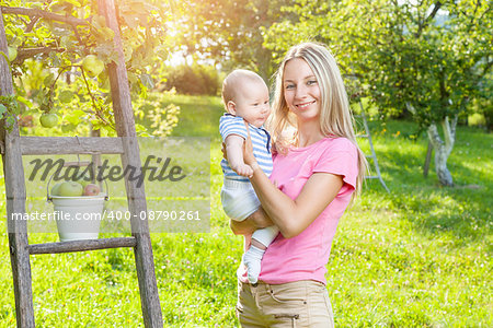 Mother with her baby picking apples from an apple tree