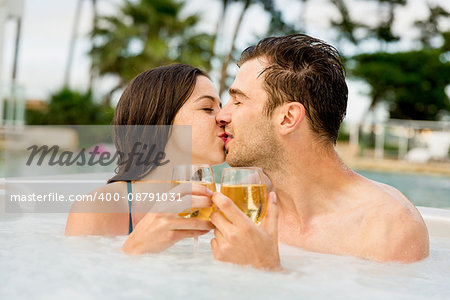 Young couple inside a jacuzzi dating and toasting