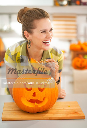 Frightful Treats on the way. happy modern housewife in the Halloween decorated kitchen with a big orange pumpkin Jack-O-Lantern