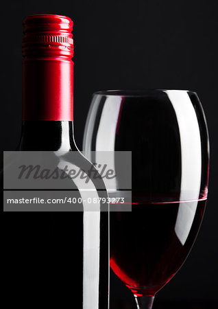 Red wine bottle and glass closeup on black background