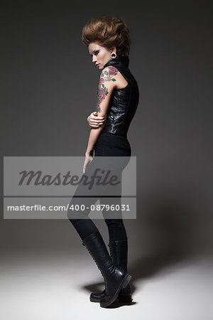 Young professional female model in black outfit and hairstyle posing in studio.