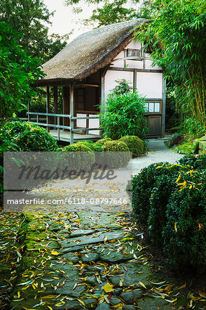 A small thatched building in a garden.