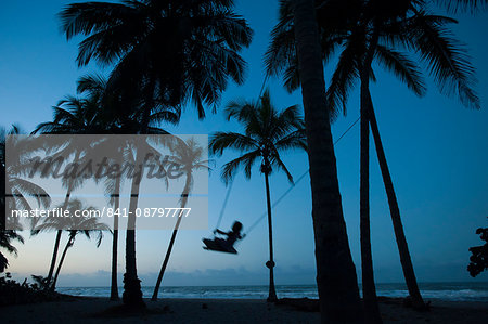 A girl plays on a swing tied between palm trees on the Carribean coast at Palomino in Colombia, South America