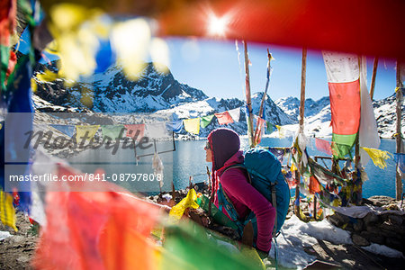 A trekker stands among prayer flags beside the holy lakes at Gosainkund in the Langtang region, Himalayas, Nepal, Asia