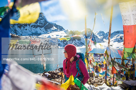 A trekker stands among prayer flags beside the holy lakes at Gosainkund in the Langtang region, Himalayas, Nepal, Asia