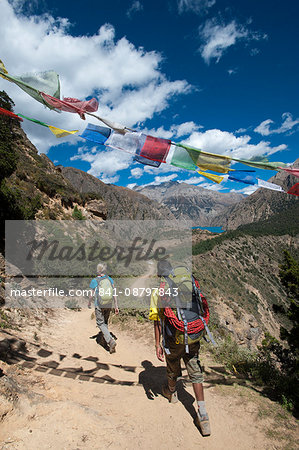 Prayer flags mark a high point in the trail where trekkers are rewarded with their first glimpse of Phoksundo Lake, Dolpa Region, Himalayas, Nepal, Asia