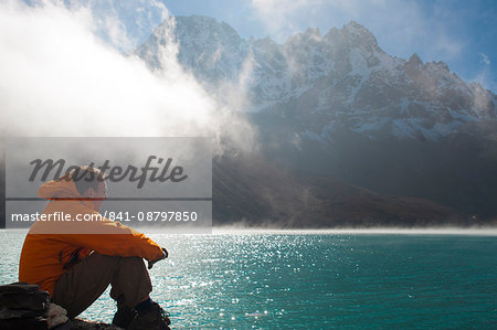 A trekker in the Everest region looks out over Gokyo Lake, Khumbu Region, Nepal, Asia