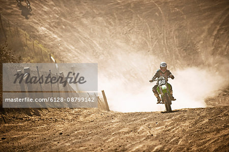 Motorbike racer racing through a dirt road.