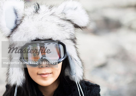 Portrait of happy young woman wearing fur hat and ski goggles