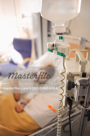 Girl lying on hospital bed with IV drip in foreground