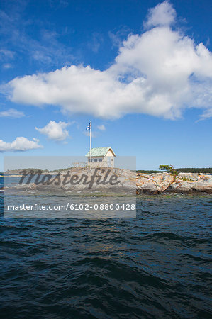 View of cottage on rock beside sea