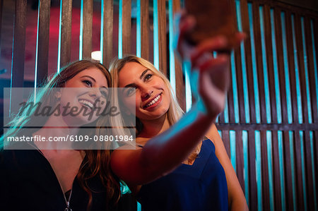 Happy friends taking selfie from mobile phone in bar