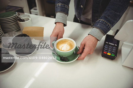 Hands serving coffee with beautiful latte art at coffee shop