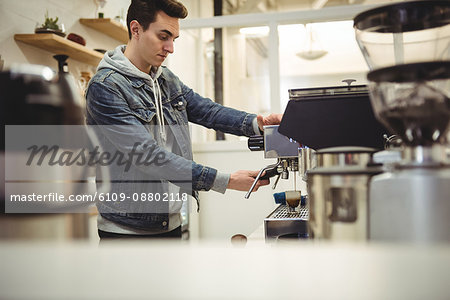 Hand of man holding portafilter under coffee machine in coffee shop