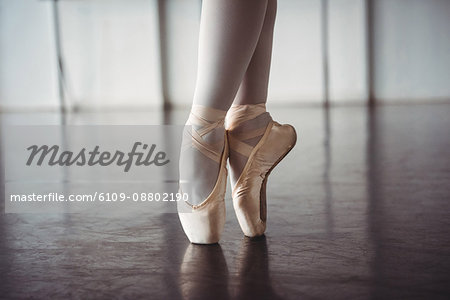 Feet of ballerina practising ballet dance in ballet studio