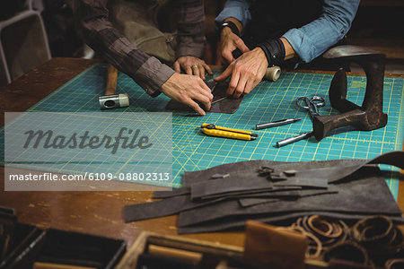 Craftswomen discussing over a piece of leather in workshop