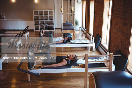 Women practicing pilates on reformer in fitness studio