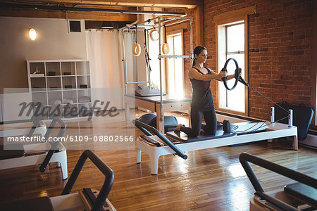 Woman practicing pilates on reformer using exercise ring in fitness studio