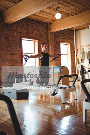 Woman practicing pilates on reformer in fitness studio