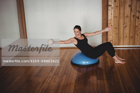 Woman doing exercise on bosu ball in fitness studio