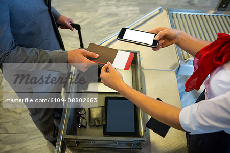Female airport staff using mobile phone to scan the passport at airport terminal Female airport staff using mobile phone to scan the passport at airport terminal
