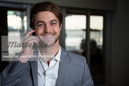 Portrait smiling businessman talking on his mobile phone in the airport terminal