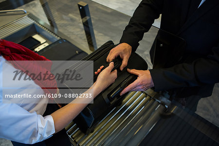 Mid section of female staff handing over luggage to businessman