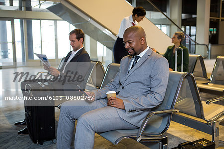 Businessman using mobile phone in waiting area at airport terminal