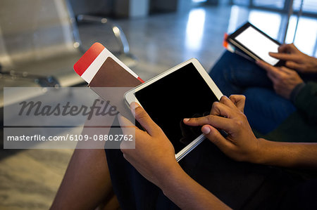 Mid-section of woman using digital tablet in waiting area at airport