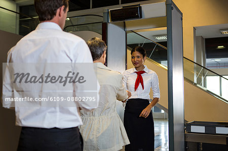 Rear view of woman handing over her boarding pass to the female staff