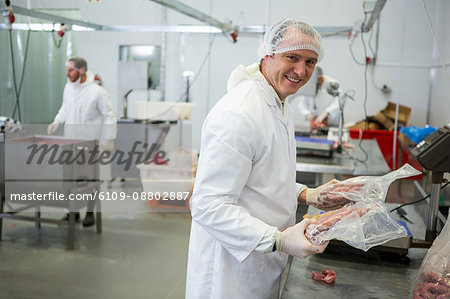 Portrait of butcher weighing packages of meat at meat factory