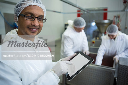 Portrait of technician using digital tablet at meat factory