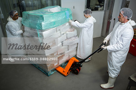 Factory staff moving boxes using a forklift at meat factory