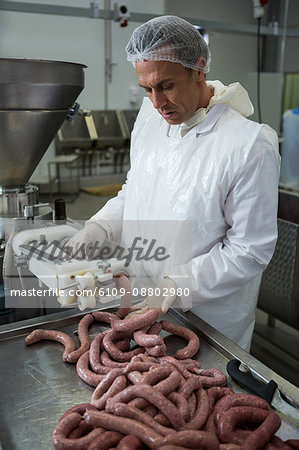 Butcher processing sausages at meat factory