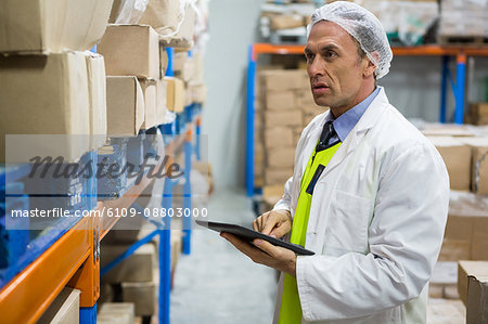 Technician maintaining records on digital tablet at meat factory