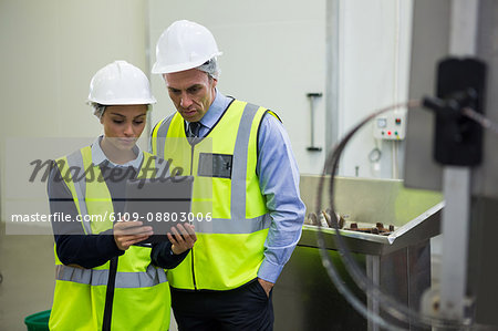 Two technician discussing over digital tablet at meat factory