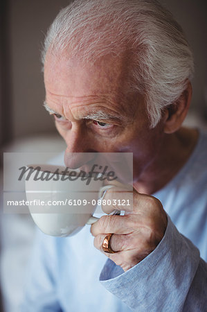 Close-up of senior man having coffee in bedroom at home