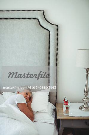 Senior woman resting on bed in bedroom at home